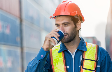 Arbeiter trinkt aus Becher am Arbeitsplatz Industrie