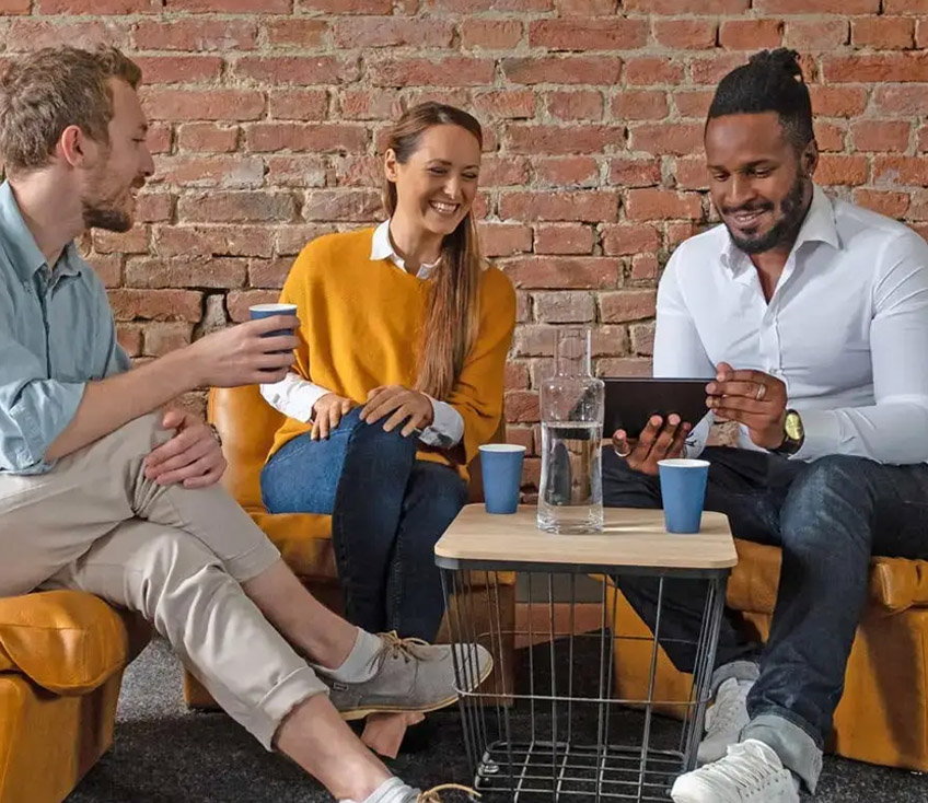 Personen sitzen gemeinsam und trinken Wasser und schauen in Tablet